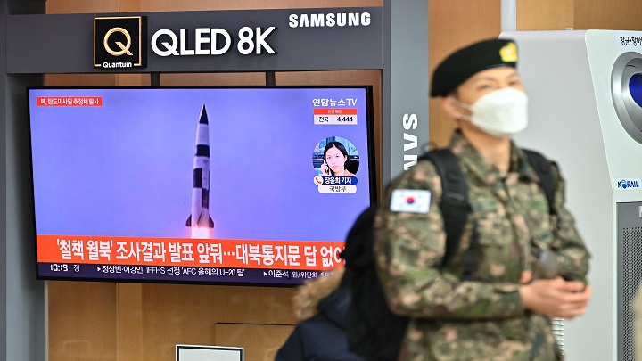 Un soldado surcoreano pasa junto a una pantalla de noticias de televisión que muestra imágenes de una prueba de misiles norcoreanos, en una estación de tren en Seúl ./ AFP