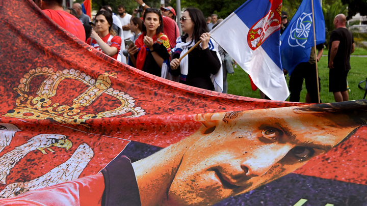 Los miembros de la comunidad serbia local sostienen banderas y pancartas frente a un centro de detención del gobierno donde el campeón de tenis de Serbia, Novak Djokovic, se encuentra en Melbourne el 8 de enero de 2022, luego de que se le negara dramáticamente la entrada a Australia por su estado de vacuna COVID-19.