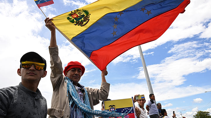 Un hombre ondea banderas venezolanas durante la ceremonia en la que se reabrió oficialmente la frontera terrestre entre Venezuela y Colombia./Foto: Yuri Cortez-AFP