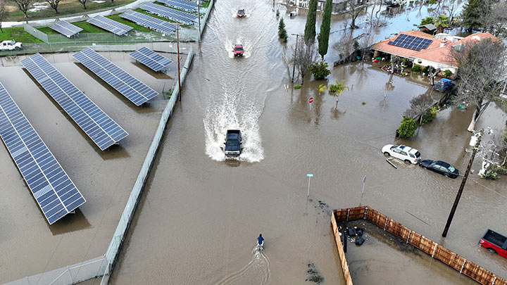 Esta vista aérea muestra autos conduciendo a través de una carretera inundada en Planada, California./Foto: AFP