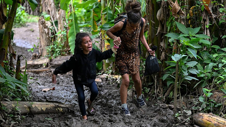 Una niña migrante venezolana es ayudada por su madre cuando llegan a la aldea de Canaan Membrillo, de la provincia de Darién en Panamá. El viaje clandestino suele durar 5 o 6 días./Fotos: AFP