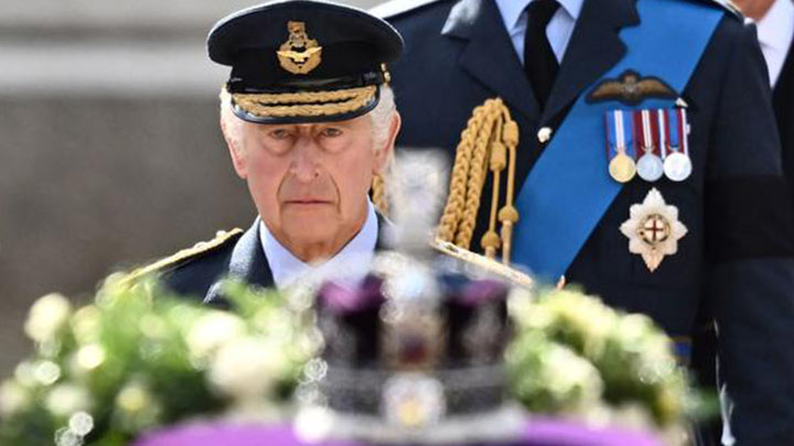 El rey Carlos III de Gran Bretaña camina detrás del ataúd de la reina Isabel II, adornado con un estandarte real y la corona del estado imperial, el 14 de septiembre de 2022./Foto: AFP