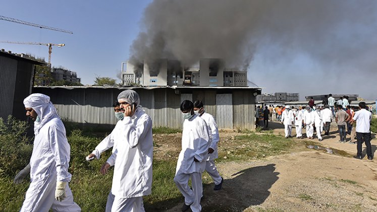 Los trabajadores con equipo de protección caminan después de que estalló un incendio en el Serum Institute de India. Foto: AFP