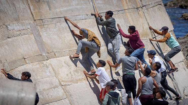 Migrantes escalan un malecón en la ciudad norteña de Fnideq después de intentar cruzar la frontera de Marruecos al enclave español de Ceuta.