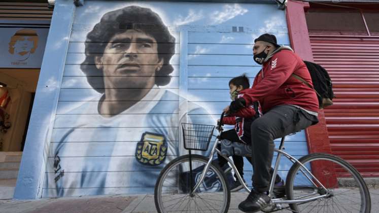 Un hombre pasa en bicicleta frente a un mural pintado por el artista Marley afuera del estadio Diego Armando Maradona. / Foto: AFP
