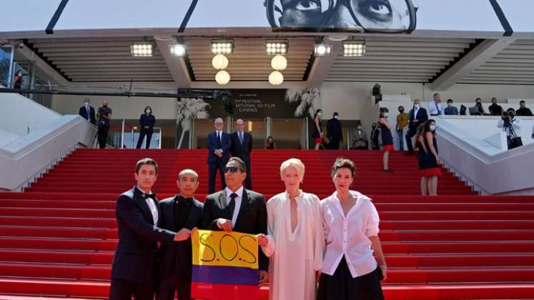 (De izquierda a derecha) El actor colombiano Juan Pablo Urrego, el director tailandés Apichatpong Weerasethakul, el actor colombiano Elkin Díaz, la actriz británica Tilda Swinton y la actriz francesa Jeanne Balibar posan con una bandera colombiana que dice "SOS" en apoyo a las protestas contra el gobierno en Colombia.
