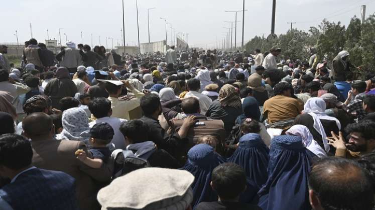 Los afganos se reúnen al borde de la carretera cerca de la parte militar del aeropuerto de Kabul, con la esperanza de huir del país después de la toma militar por los talibanes. / AFP