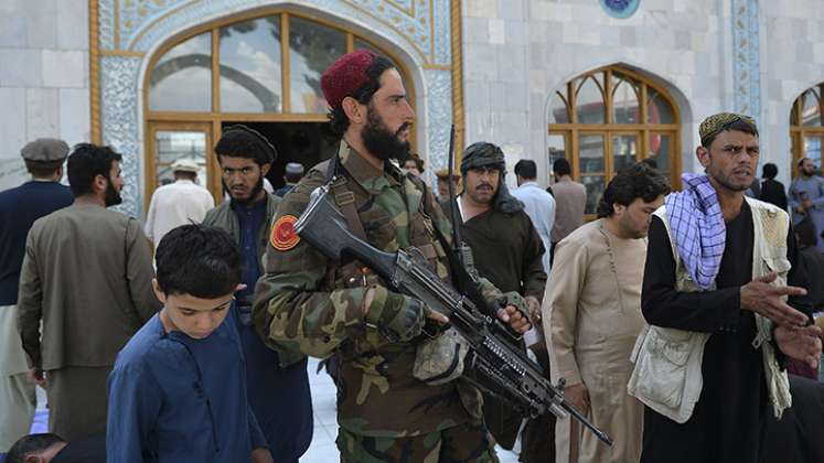 Un combatiente armado talibán hace guardia mientras los devotos musulmanes se van después de las oraciones.