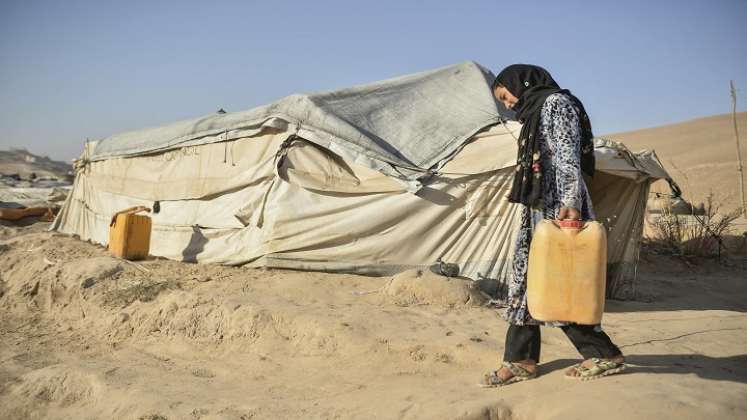Una niña que vive con su madre pero que debería haber ido a reunirse con la familia de su futuro cónyuge hace un mes, cargando un bidón lleno de agua. / AFP